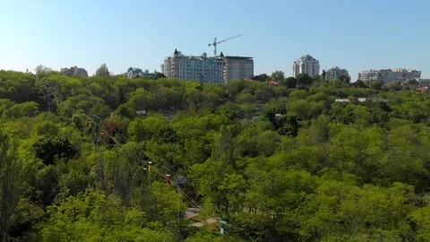 Cableway with moving multicolor booths over green park, stadiums, buildings  Vídeo Stock 89653509