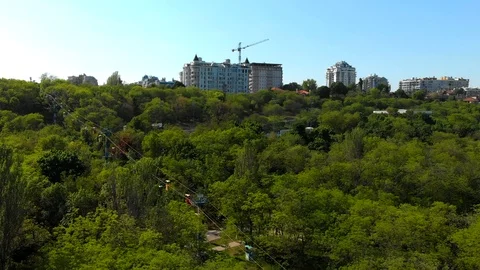 Cableway with moving multicolor booths over green park, stadiums, buildings  Video stock 89653630