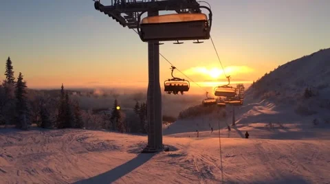 Cableway in the rays of the setting sun among snow-capped mountains Stock-Footage 61668883
