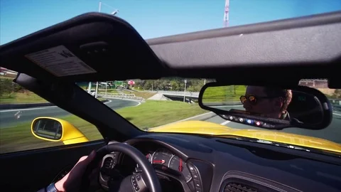 Cabriolet Corvette driver's portrait in back mirror. Car is driving along road Stock Footage 85104670