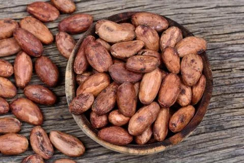 Cacao beans in a bowl on rustic table Stock Photos