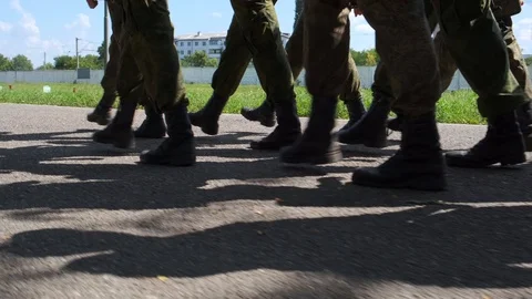 Cadets, soldiers marching in a group along the wet road in black boots and Stock Footage 125493129