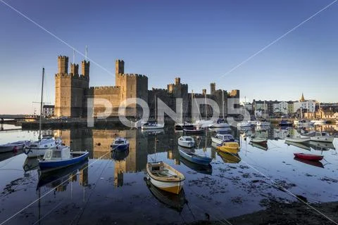 Caernarfon castle and harbour with boats and reflections Stock Photos