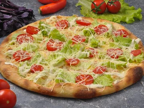 Caesar pizza on a gray background decorated with vegetables Stock Photos