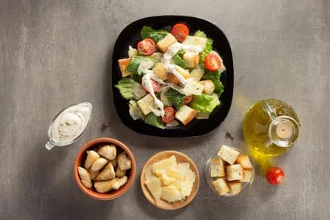 Caesar salad and ingredients at table Stock Photos