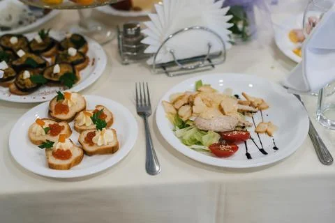 Caesar salad and other various snacks on the festive table Stock Photos