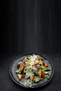 Caesar salad on a black plate. Vertical Stock Photos