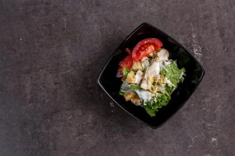 Caesar salad in a black plate . the view from the top Stock Photos
