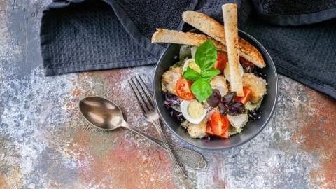 Caesar salad with chicken, cherry tomatoes, croutons and basil in a dark blue Stock Photos