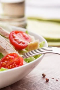 Caesar salad with chicken on a light natural table with cutlery. Stock Photos
