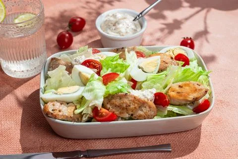 Caesar salad with chicken in a white plate on the table. Stock Photos