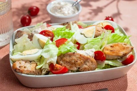Caesar salad with chicken in a white plate on the table. Stock Photos