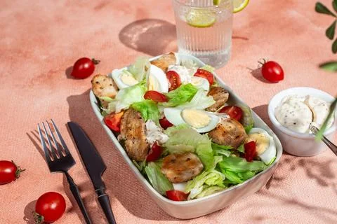 Caesar salad with chicken in a white plate on the table. Stock Photos