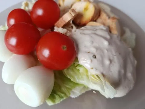 Caesar salad with crisp lettuce, cherry tomatoes, halved quail eggs, crunchy Foto stock