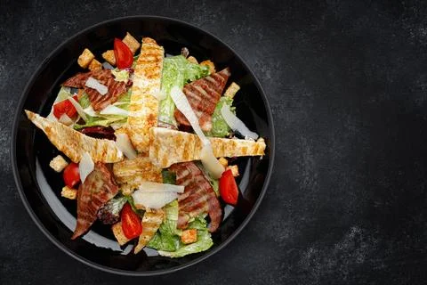 Caesar salad with crispy bacon, grilled chicken, and Parmesan cheese Stock Photos