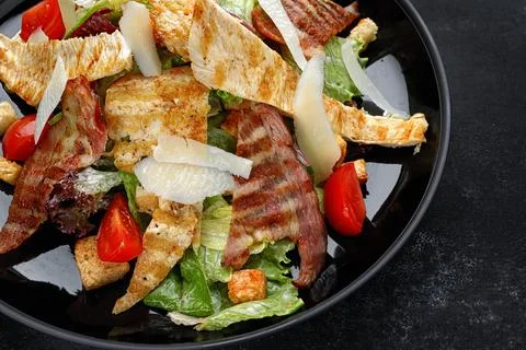 Caesar salad with crispy bacon, grilled chicken, and Parmesan cheese Stock Photos