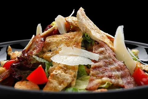 Caesar salad with crispy bacon, grilled chicken, and Parmesan cheese Stock Photos