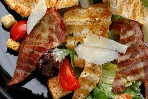 Caesar salad with crispy bacon, grilled chicken, and Parmesan cheese. close-u Stock Photos