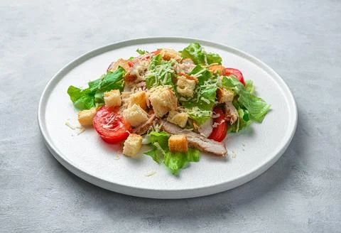 Caesar salad on a flat plate on a gray background. Minimalistic culinary back Stock Photos