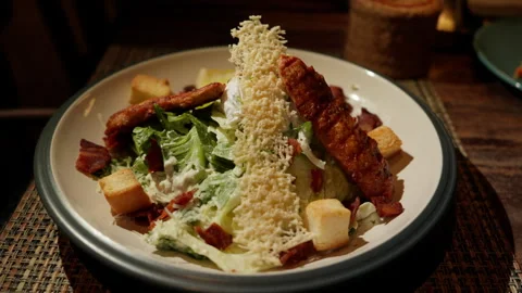 Caesar salad graces the dining table. The vibrant greens, crispy croutons , Video stock 248579231