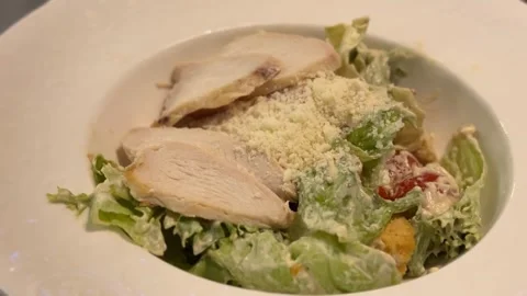 Caesar salad with grilled chicken and parmesan cheese in white bowl on tabl.. Stock Footage 329469013