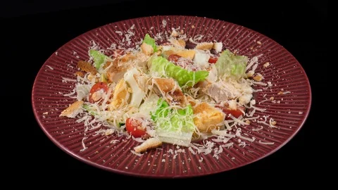 Caesar salad isolated on black background in red plate, loop Video stock 91031437