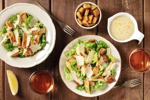Caesar salad, overhead flat lay shot with croutons, sauce and wine on a dark Stock Photos