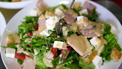 Caesar salad pick up salad with cheese pieces using a fork Stock Footage 285023766