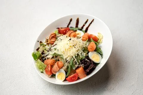 Caesar salad with red fish and grated Parmesan cheese. Food plate on white Stock Photos