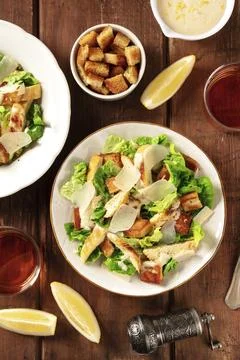 Caesar salad a rustic wooden table, with wine, lemon slices and croutons Stock Photos