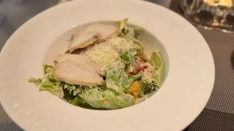 Caesar salad with sliced chicken and parmesan cheese, served in a white bow.. Stock Footage 331285886