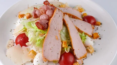 Caesar salad with sliced grilled chicken breast, quail eggs and bacon on top Stock Footage 87326871
