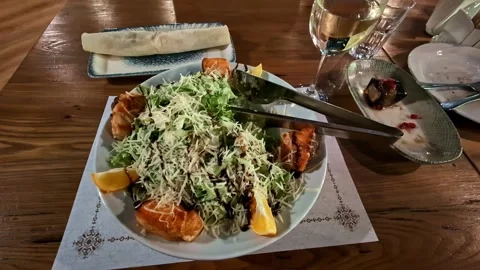 Caesar salad topped with grilled salmon seafood garnished with lemon wedges Stock Footage 337925784