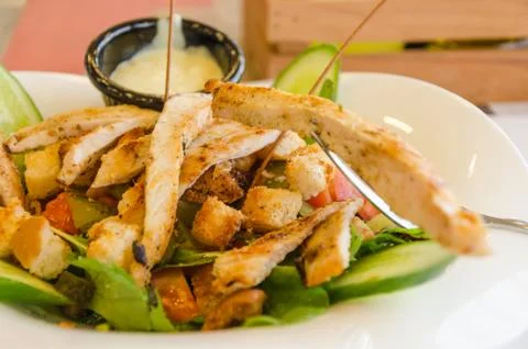 The caesar salad was served on a white plate with fresh salad leaves and sauc Stock Photos
