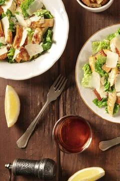Caesar salad with wine and lemons, top flat lay shot on a dark rustic wooden Stock Photos