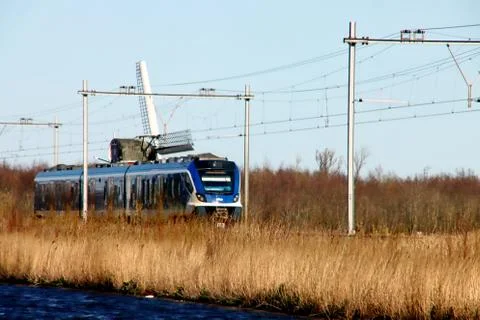 CAF Civity sprinter train of NS drives along windmill at Noordwijkerhout Stock Photos