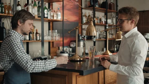 In the Cafe Beautiful Hispanic man Makes Takeaway Coffee For a Customer Who Pays Stock Footage 89972047