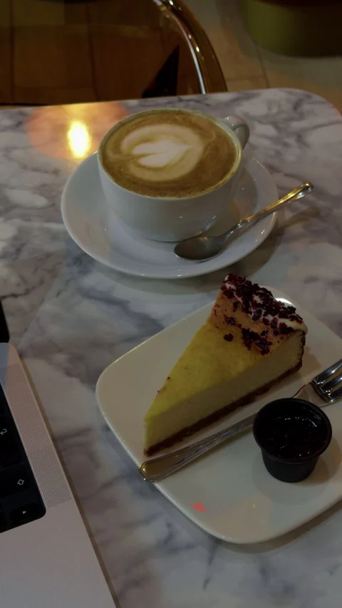 Cafe latte and cheesecake on marble table with warm reflection and cozy dessert Stock Footage 344966386