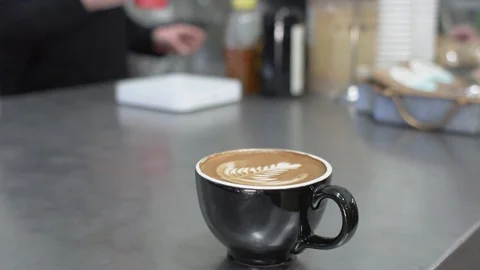 Cafe latte espresso in a small black mug with foam art Stock Footage 122861869