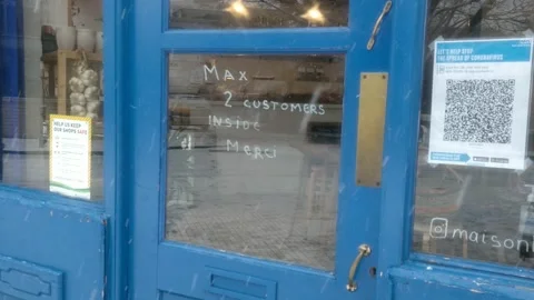 A CAFE IN LONDON WITH QR CODE ON DOOR DURING COVID-19 WHILE ITS SNOWING Stock Footage 147129789