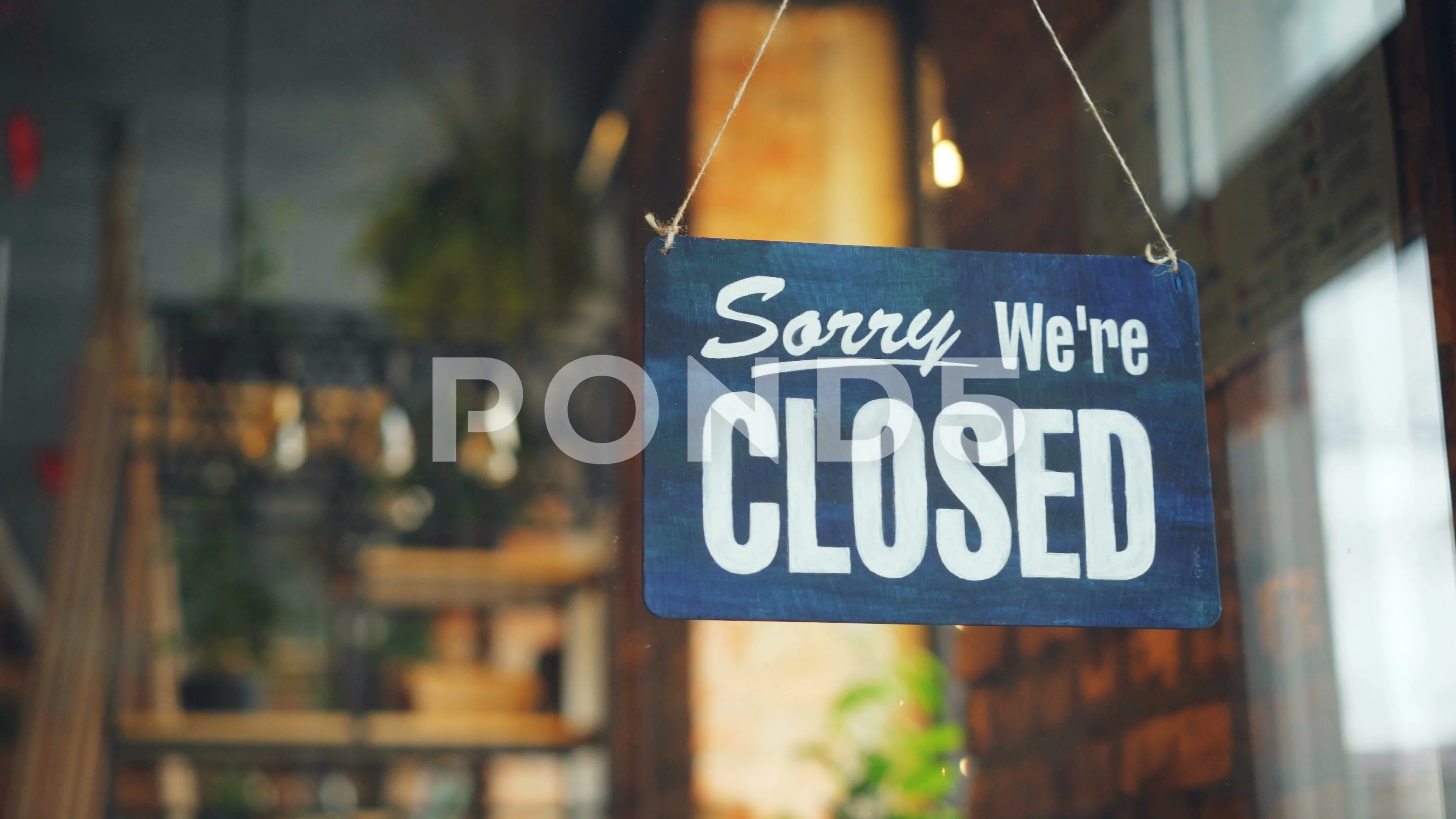 Cafe manager changing closed to open sign on window smiling looking outside