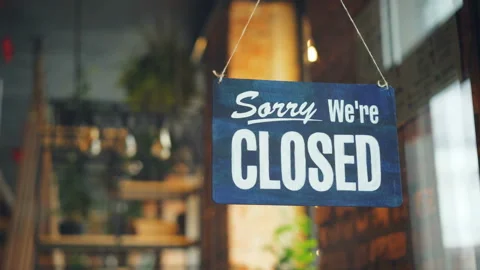 Cafe manager changing closed to open sign on window smiling looking outside