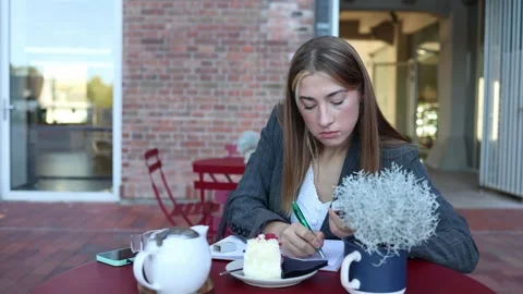 Cafe manager completes daily paperwork at an outdoor table during work break Stock Footage 345028400