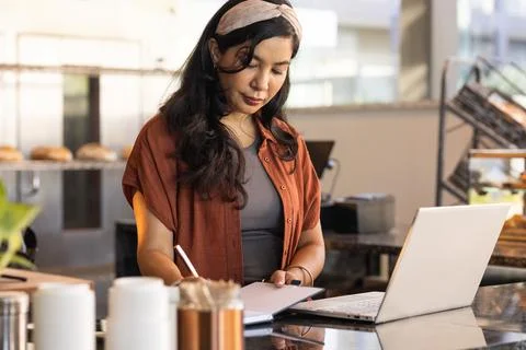 Cafe manager writing in notebook after laptop alert, animated inventory icons Stock Photos
