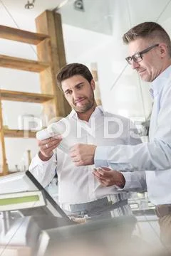 Cafe owner and waiter reviewing receipt at cash register Stock Photos