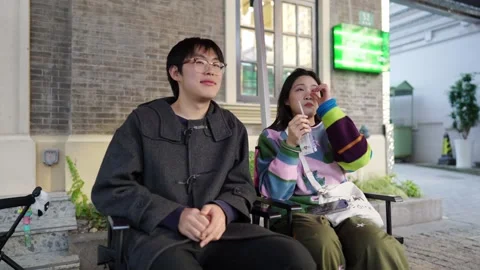 A cafe on a public road where many people walk in Shanghai, China. A young 動画素材 301445366