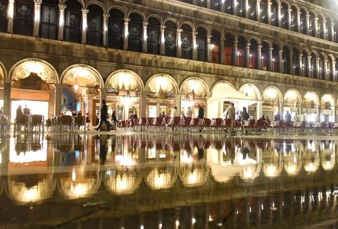 Cafe on San Marco square with reflection on water at night in Venice. Stock-Fotos