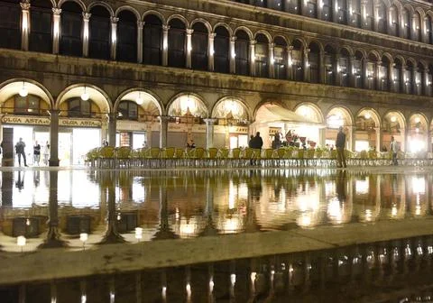 Cafe on San Marco square with reflection on water at night in Venice. Stock Photos