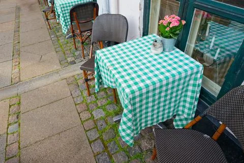 Cafe sidewalk seating with checkered tablecloths small vases Stock Photos