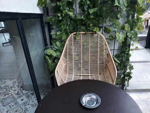 A café table and chairs with stone floors and plant decorations on the walls 스톡 사진